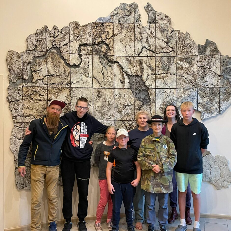 Kopbilde ar jaunejiem reindžeriem un skolotājiem pie mākslas objekta.