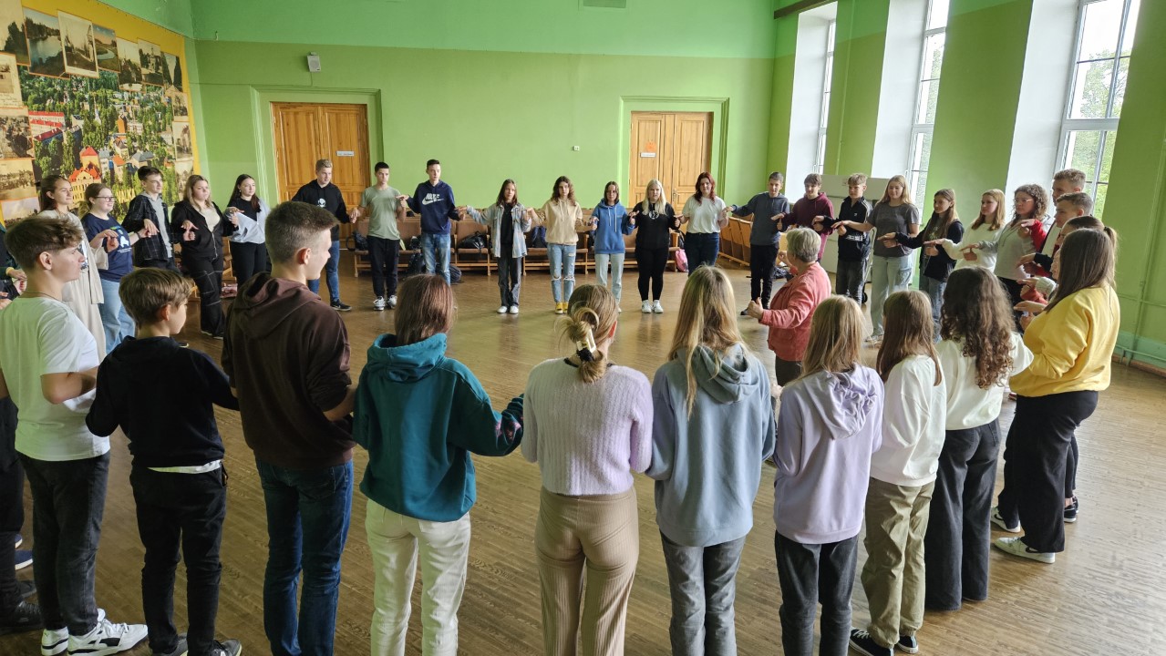Skolēnu pašpārvalde sadevušies rokās, veidojot apli.